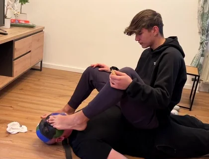 German master sitting on feet licking boy
